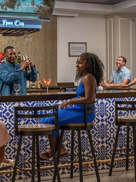 Guests on high stools by a blue tiled bar in Rum Cay Lobby Bar at Warwick Paradise Island Bahamas