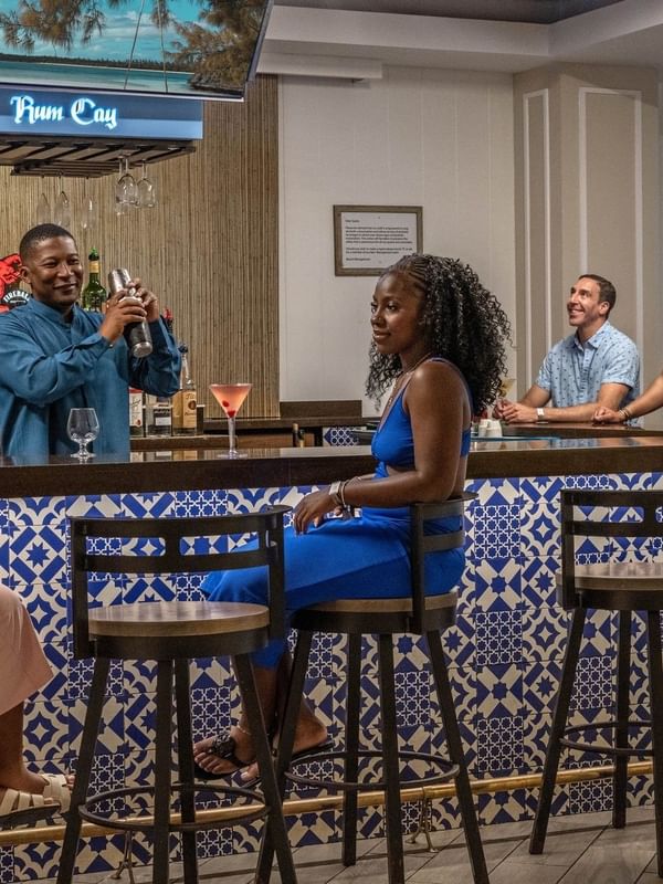 Guests on high stools by a blue tiled bar in Rum Cay Lobby Bar at Warwick Paradise Island Bahamas