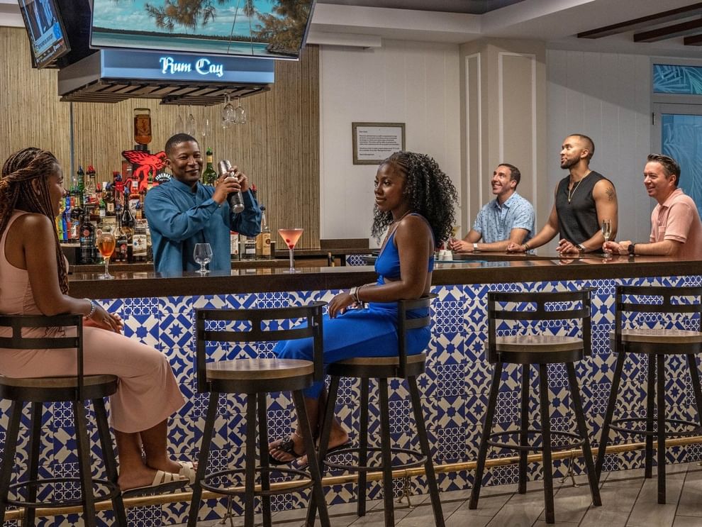 Guests on high stools by a blue tiled bar in Rum Cay Lobby Bar at Warwick Paradise Island Bahamas
