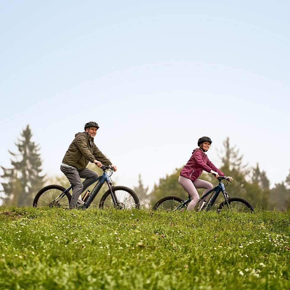 Zwei Radfahrer auf E-Bikes in einer grünen Landschaft bei einem E-Bike Wochenende.