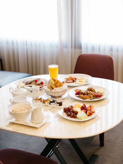 Breakfast spread on a table with pancakes, fruits, pastries and juice In Room Dining at Sofitel Brisbane Central