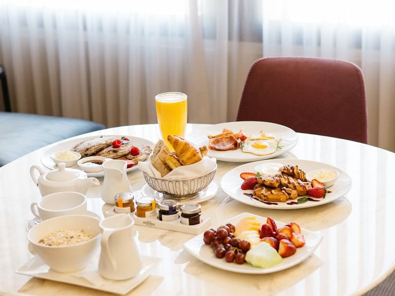 Breakfast spread on a table with pancakes, fruits, pastries and juice In Room Dining at Sofitel Brisbane Central