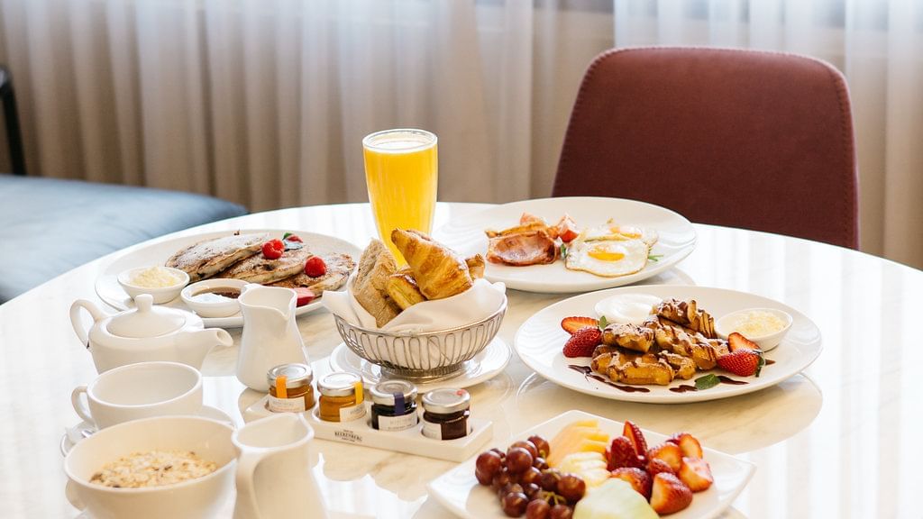 Breakfast spread on a table with pancakes, fruits, pastries and juice In Room Dining at Sofitel Brisbane Central