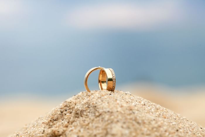 Close-up of wedding rings on sand, Thunderbird Beach Resort