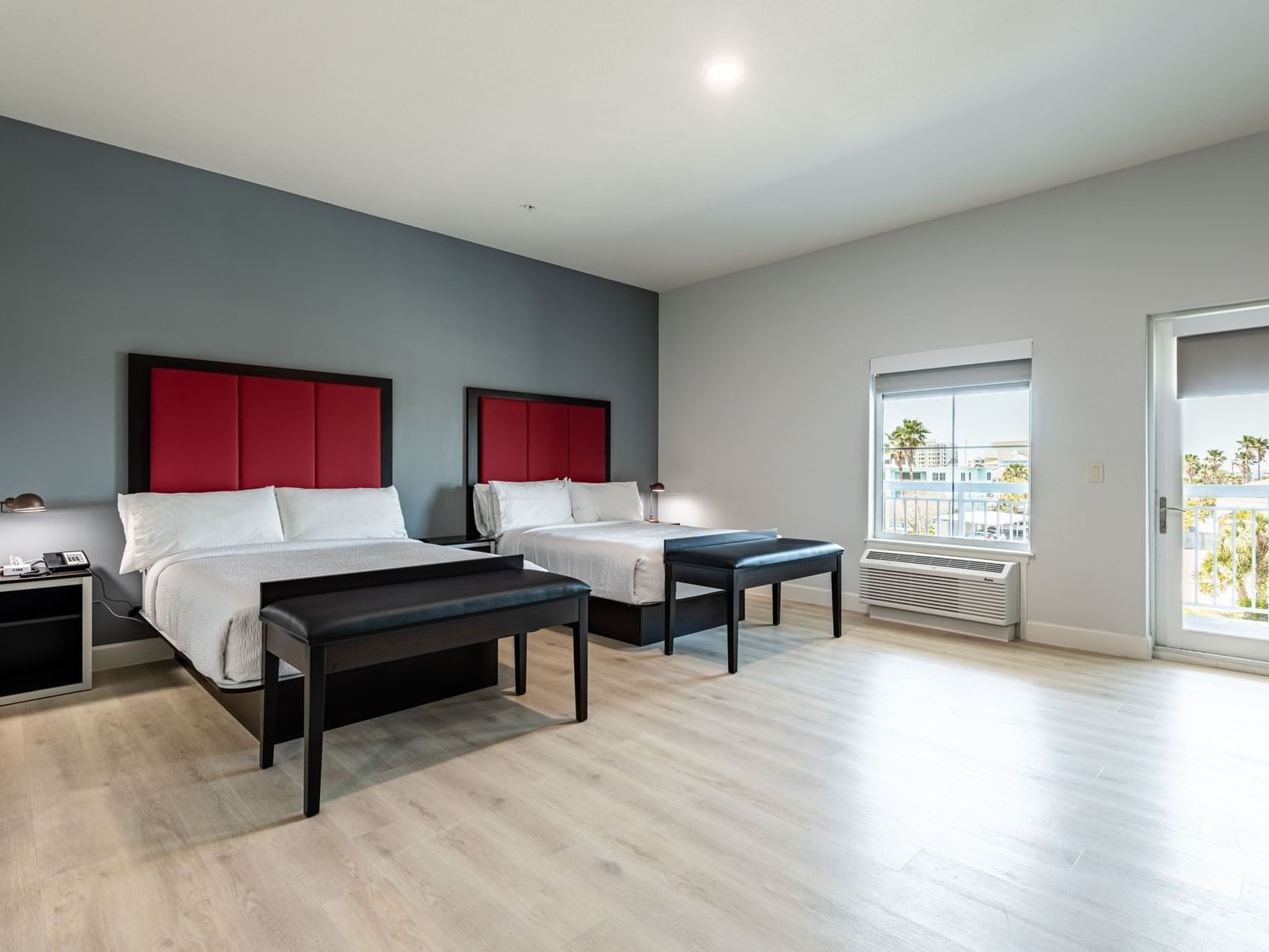 Comfy beds with cushioned headboards and an outdoor view through a large window in Double Queen with Balcony at The J Hotel
