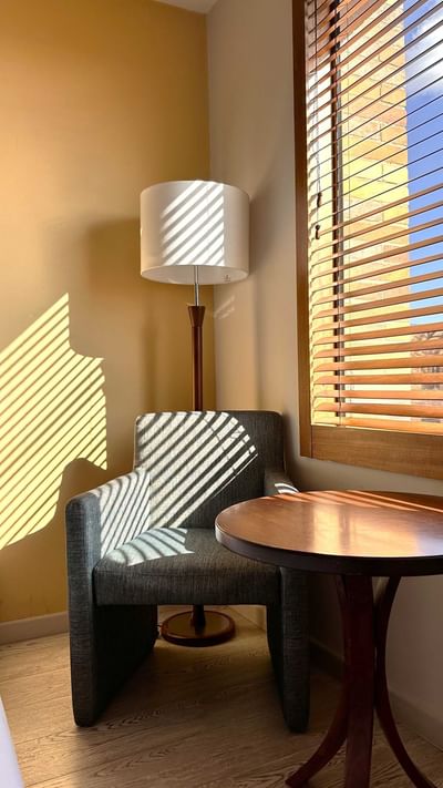 A cozy armchair and a small table bathed in sunlight from the window in Standard Queen at the Habitel Hotel Select