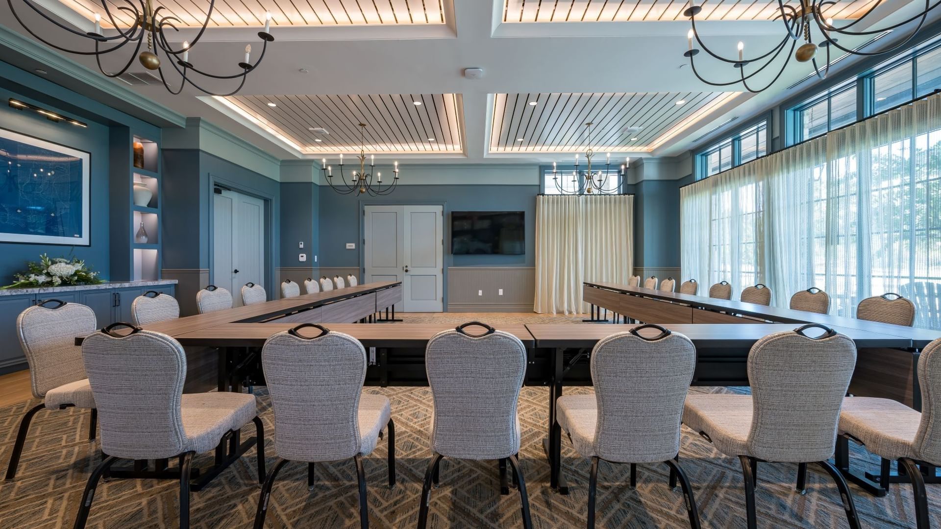 Club Room with U-shaped table setup, upholstered chairs, and elegant chandeliers at Camp Creek Inn in Inlet Beach