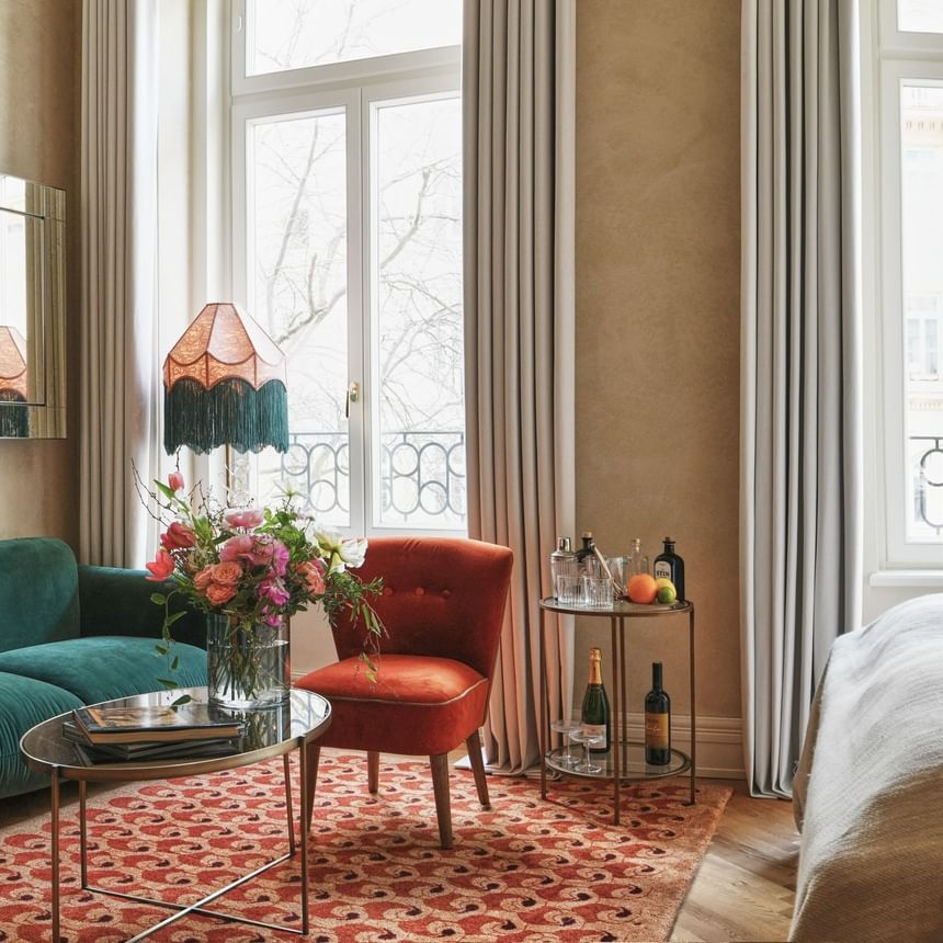 Cozy lounge area and liquor by the bed in Deluxe Room with large windows and elegant decor at Hotel Motto Vienna