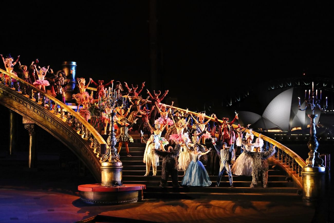 A man and woman in Phantom of the Opera costumes on stage with raised arms.