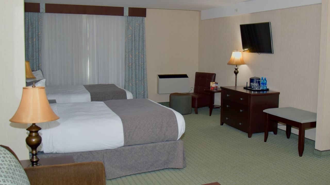 Hotel room with two beds, a desk, a chair, and a mounted television.