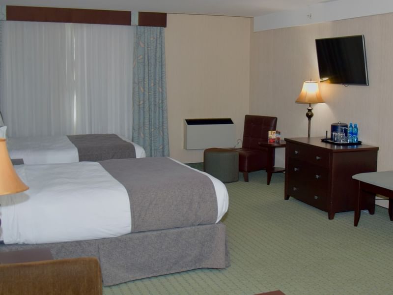 Hotel room with two beds, a desk, a chair, and a mounted television.