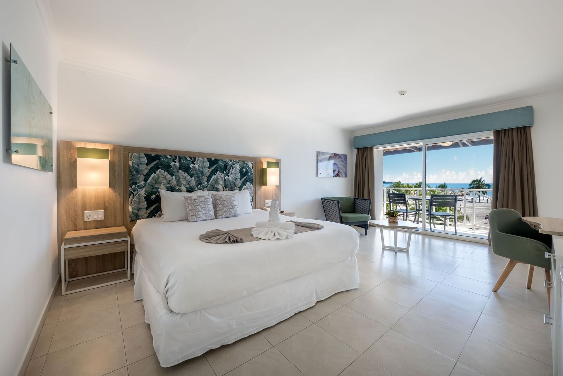 Playa Blanca Beach Resort bedroom with a large bed, seating area, and balcony overlooking the ocean.