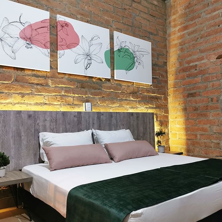 Comfy bed in a room with brick walls at Botanica Casa Hotel