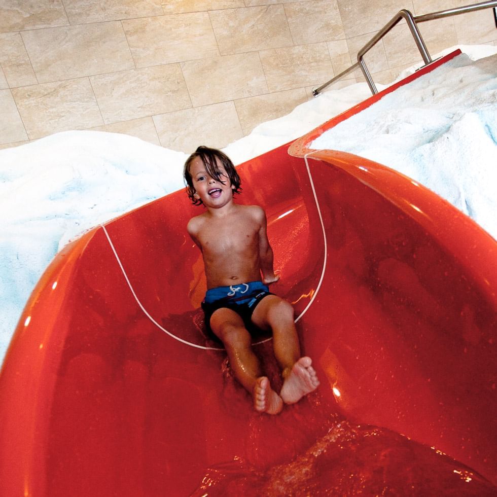 A boy in a water slide at Falkensteiner Hotels

