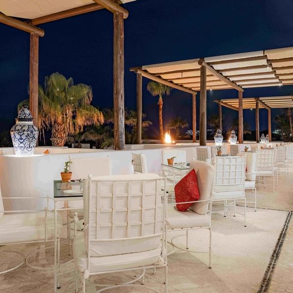 Terraza del restaurante Vista Ballenas con mesas y sillas al aire libre de noche en el Marquis Los Cabos Resort & Spa.