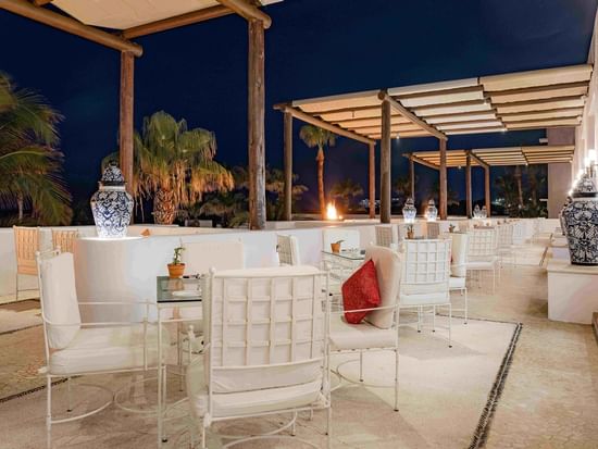 Outdoor dining area in Vista Ballenas at Marquis Los Cabos Resort at night with comfortable seating and soft lighting