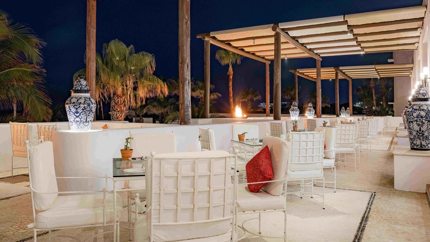 Outdoor dining area in Vista Ballenas at Marquis Los Cabos Resort at night with comfortable seating and soft lighting