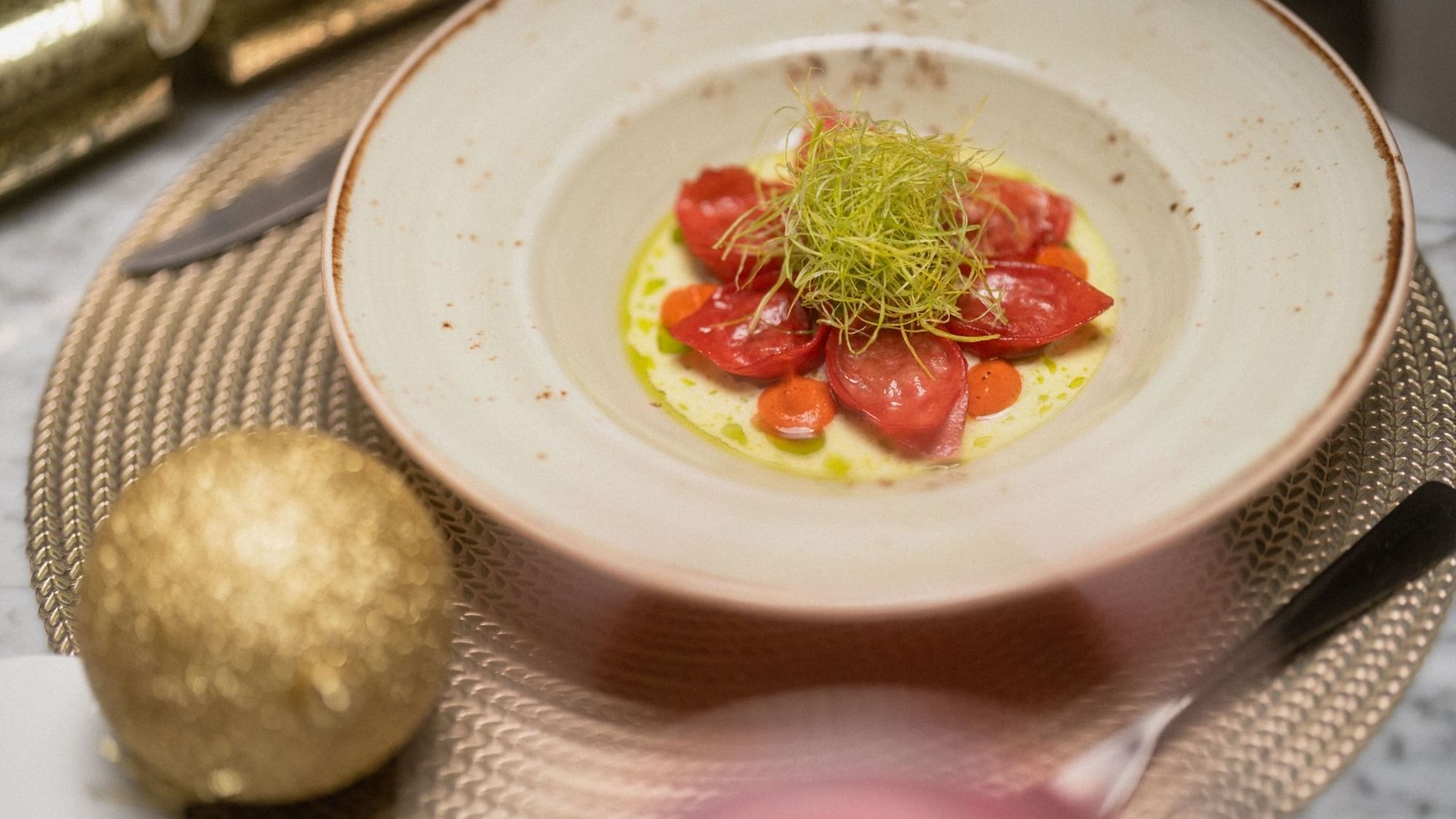 Beautifully plated appetizer with red tomatoes and green garnish in a shallow bowl at Paramount Hotel Midtown