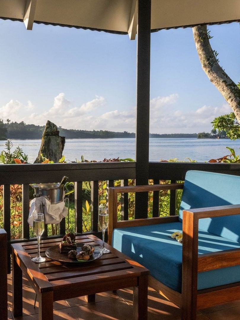 Balcony with blue chairs and table set with champagne and sweet treats in Lagoon Bungalow at warwick le lagon-vanuatu