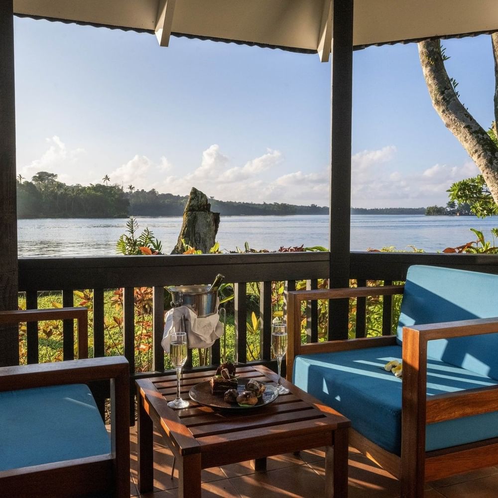 Balcony with blue chairs and table set with champagne and sweet treats in Lagoon Bungalow at warwick le lagon-vanuatu