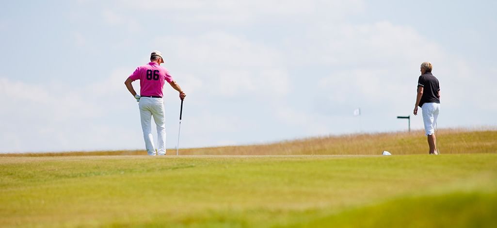 man in a pink shirt playing golf with partner