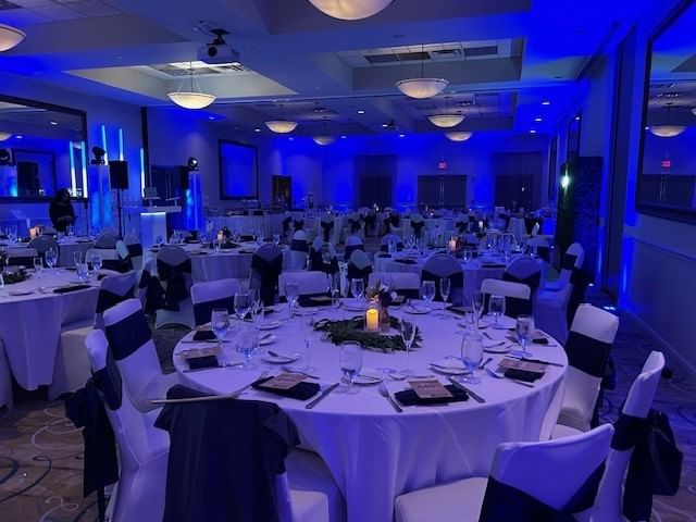 a large meeting room with round tables and blue lighting
