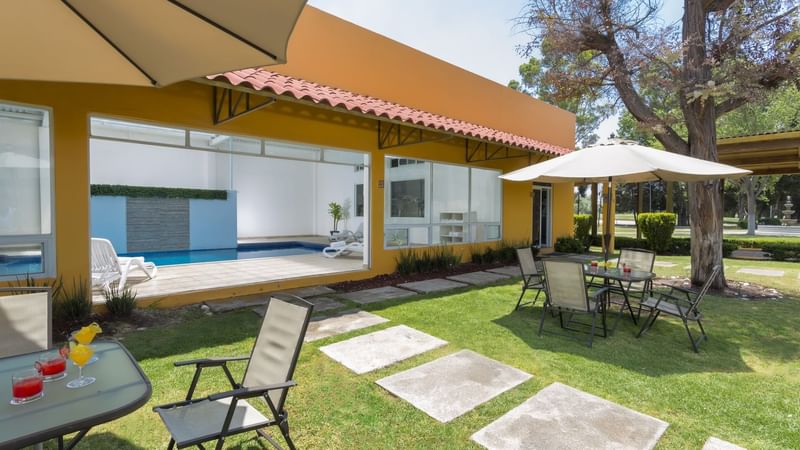 Outdoor dining tables set up with canopies and the indoor pool area at Hotel Gamma Pachuca