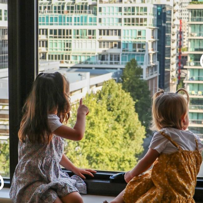 Two little girls looking out from their hotel window at Pullman Albert Park