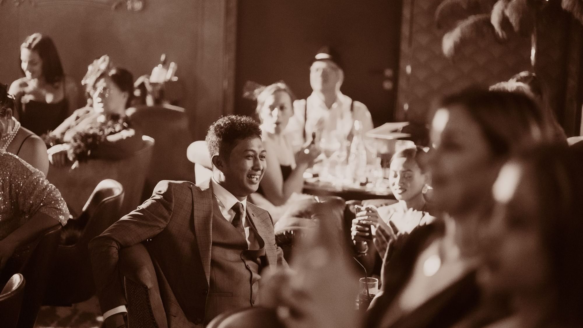 Sepia-toned image of people enjoying drinks and conversation in a Flashback Speakeasy Bar at Paramount Hotel Dubai