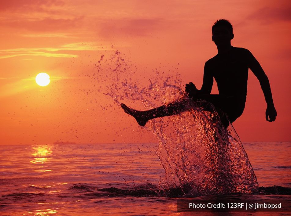 Man splashing sea water in Port Dickson sunset