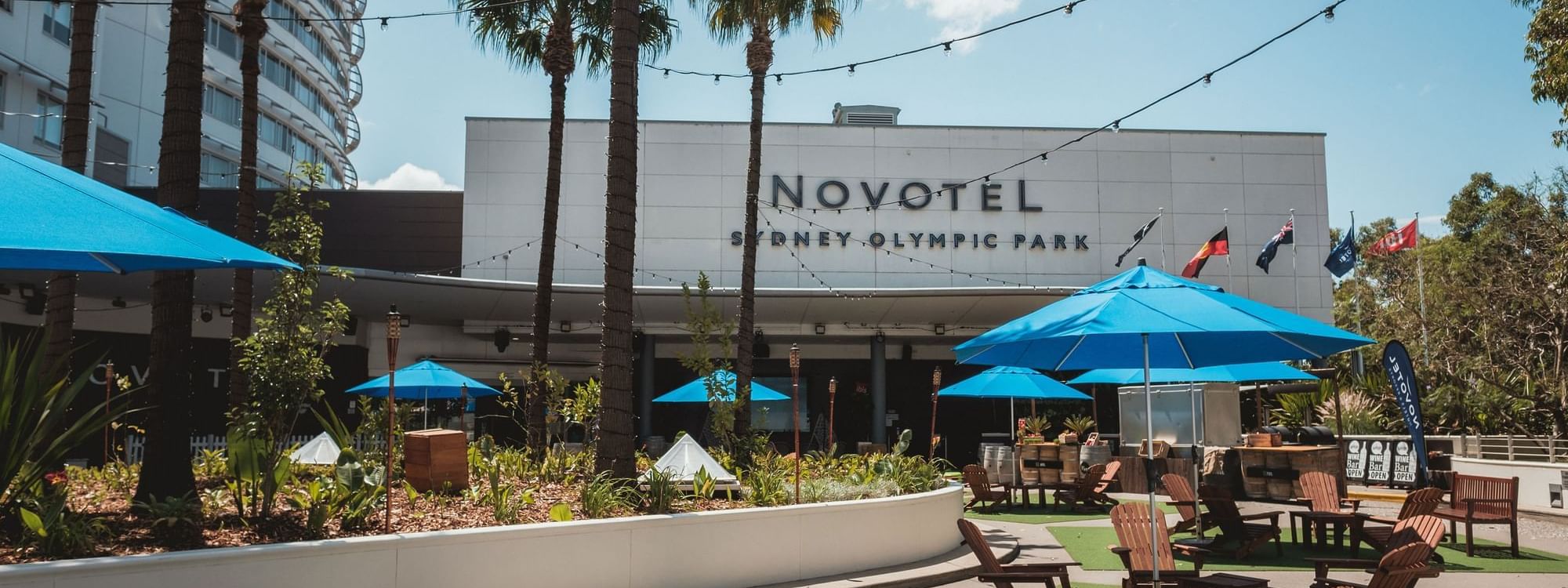 Exterior view of Novotel Sydney Olympic Park featuring the open-air lounge area at The Driveway