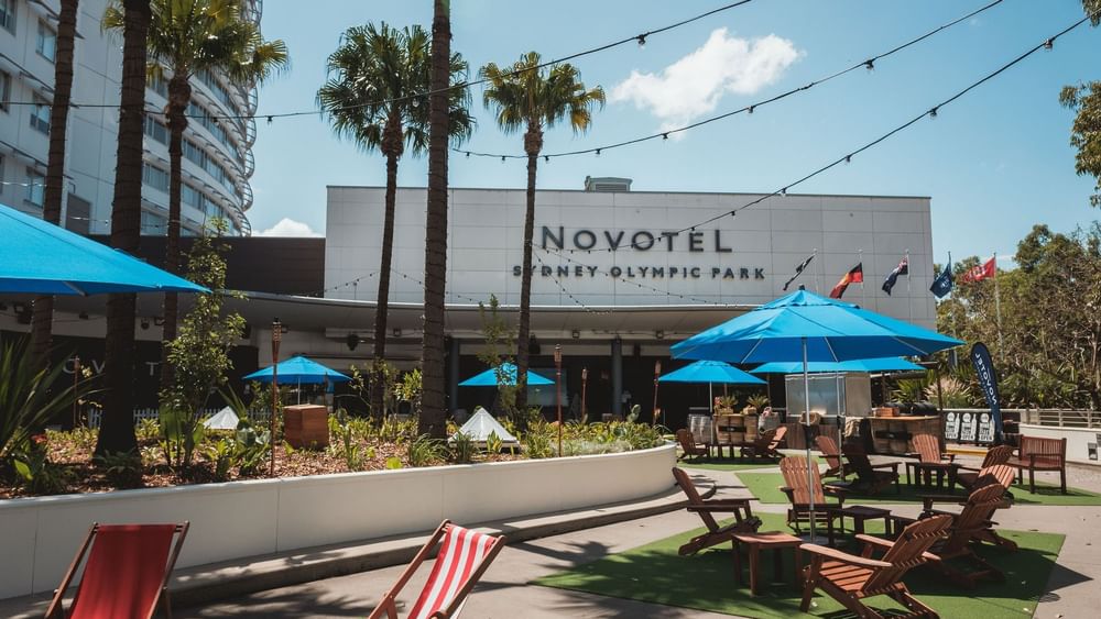 Exterior view of Novotel Sydney Olympic Park featuring the open-air lounge area at The Driveway