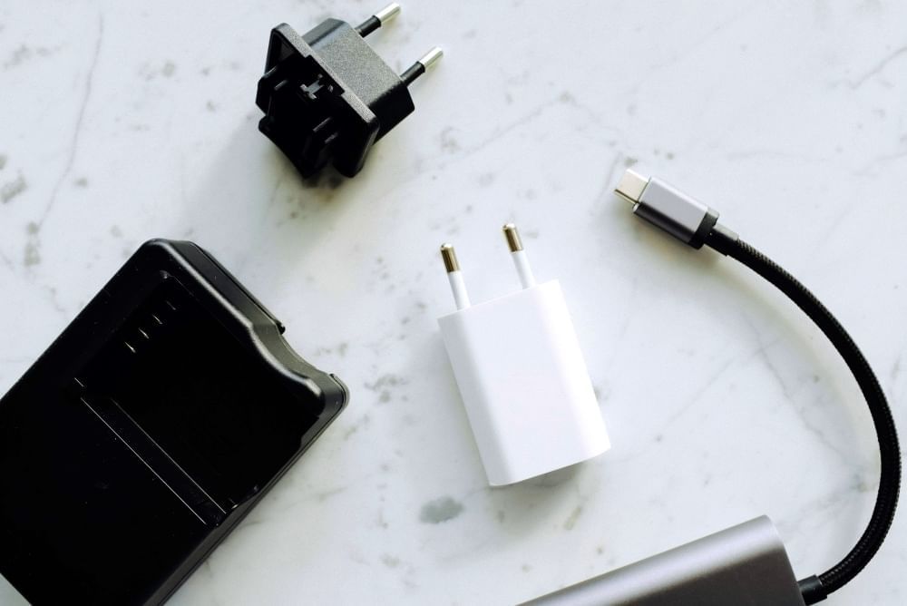 Black and white adapters laying on a white marble countertop.