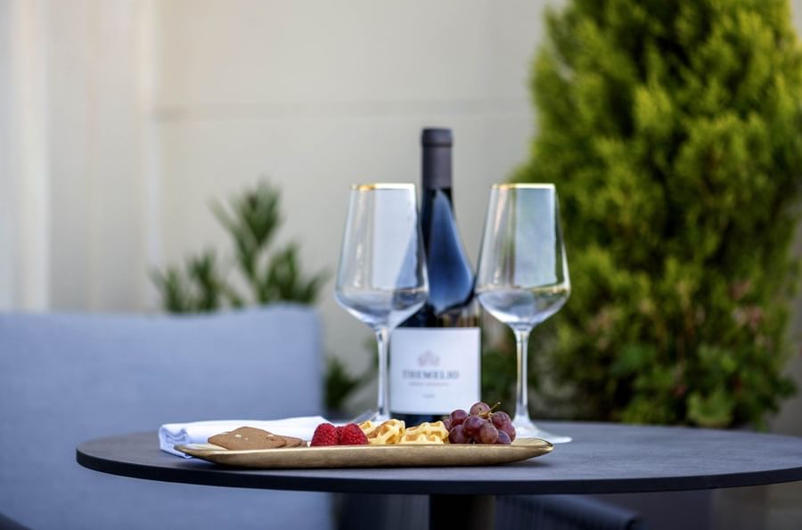 Close-up of wine bottle & glasses, and waffles on outdoor table in Junior Suite with terrace at Hotel Barsey by Warwick