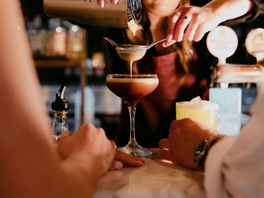 Bar tender pouring an Espresso Martini by the counter in Bar 649 at Amora Hotel Riverwalk Melbourne