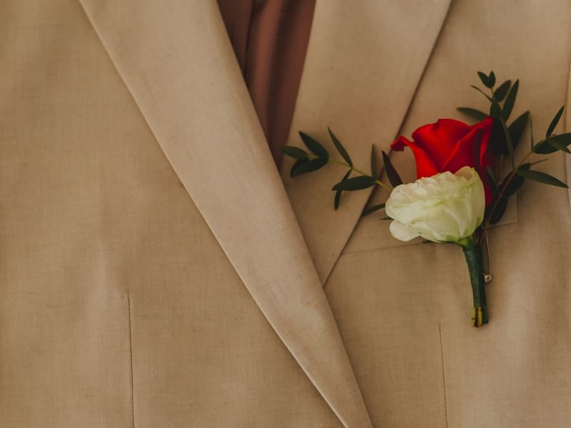 Groom in a tan suit with a boutonniere of red and white roses at Riviera Nayarit Resort & Spa.