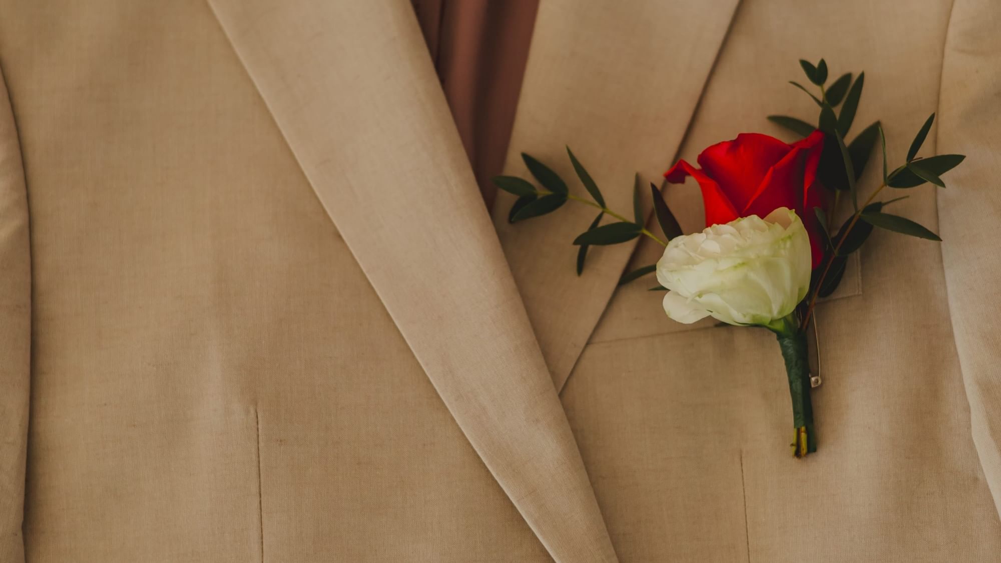 Groom in a tan suit with a boutonniere of red and white roses at Riviera Nayarit Resort & Spa.