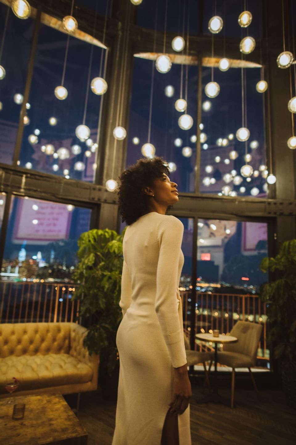 A lady in white dress standing in the lobby area just looking upside