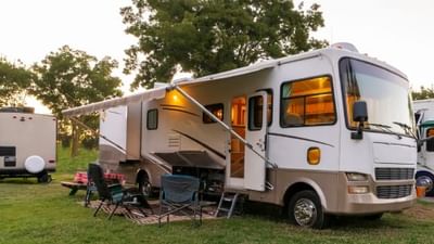 Large motorhome parked at a campsite with its awning extended and camping chairs set up at Fall Creek Marina & Campground