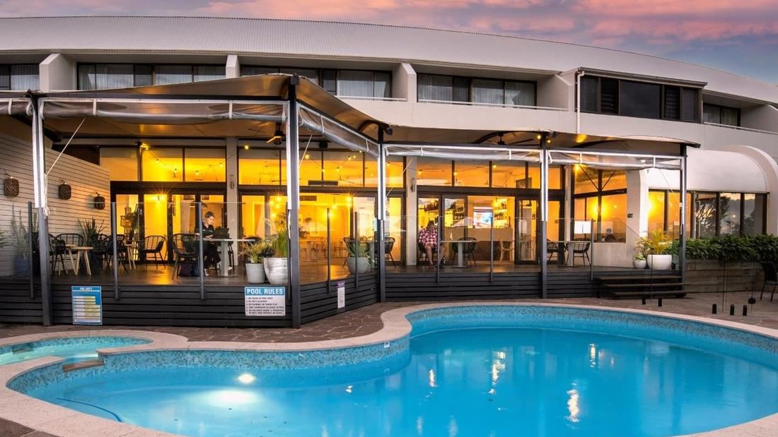 Exterior view of Madison Kitchen + Bar with an open dining area overlooking the outdoor pool at Mercure Charlestown