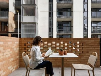 Mature-aged student studying at a table on outdoor patio, with Swift Walk apartment buildings in view.