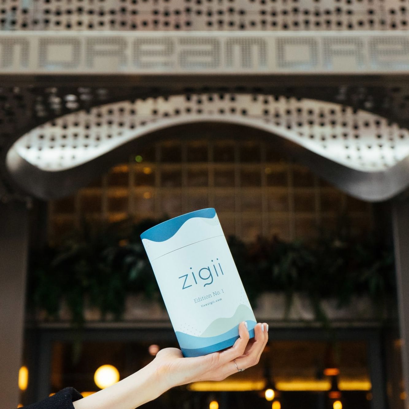 A bottle of 'zigii' on a women's hand with Dream Hotel view.