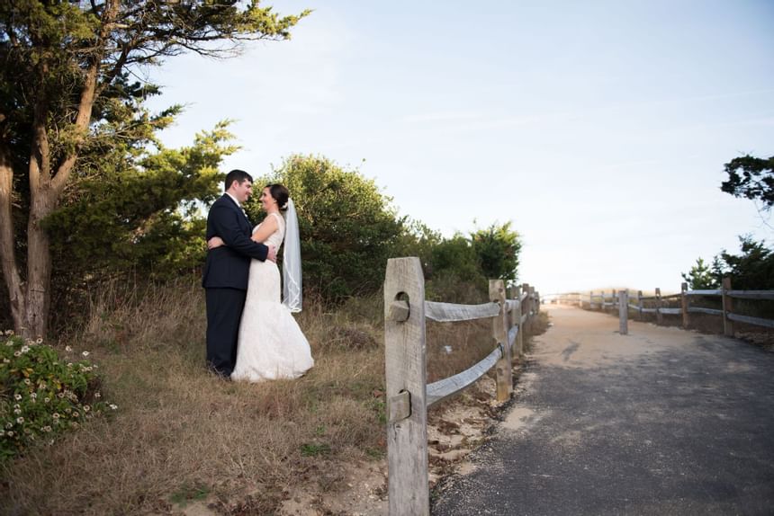 Bride and groom pose for a photo by the beach near our Avalon wedding venue