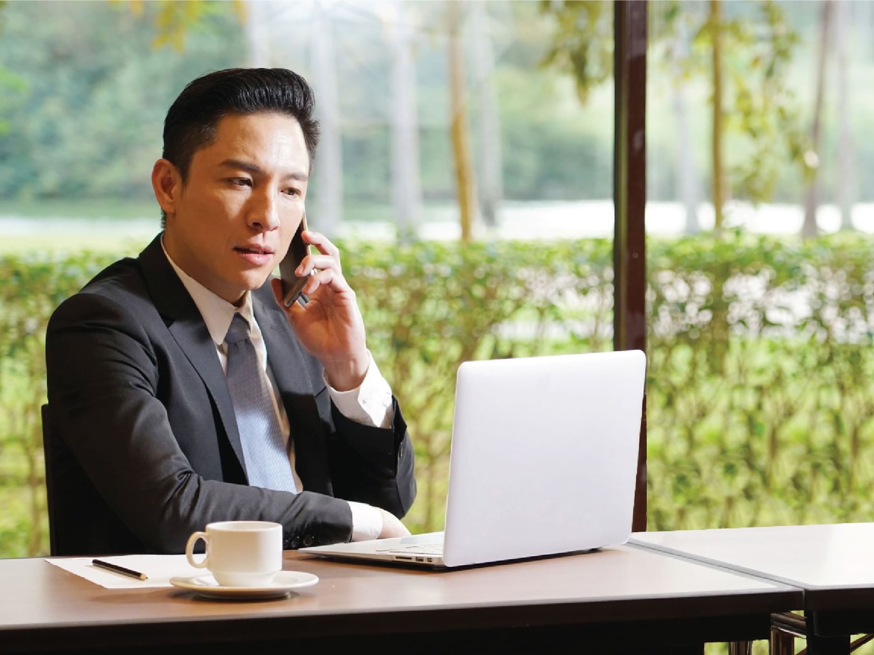 Gentleman making a call, while working on the laptop at Saujana Hotel Kuala Lumpur