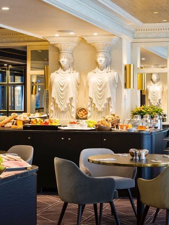 Breakfast buffet featuring bowls of fruit with Greek Caryatid statues in The Avenue Restaurant at Hotel Barsey by Warwick 