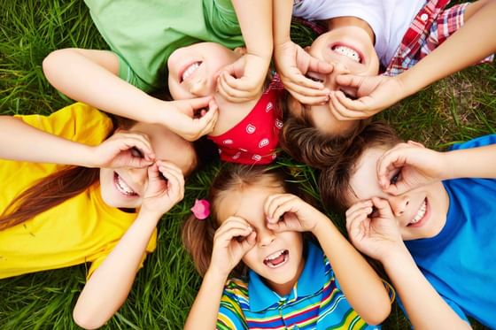 Children laying on the grass making binoculars with their hands at The Danna Langkawi