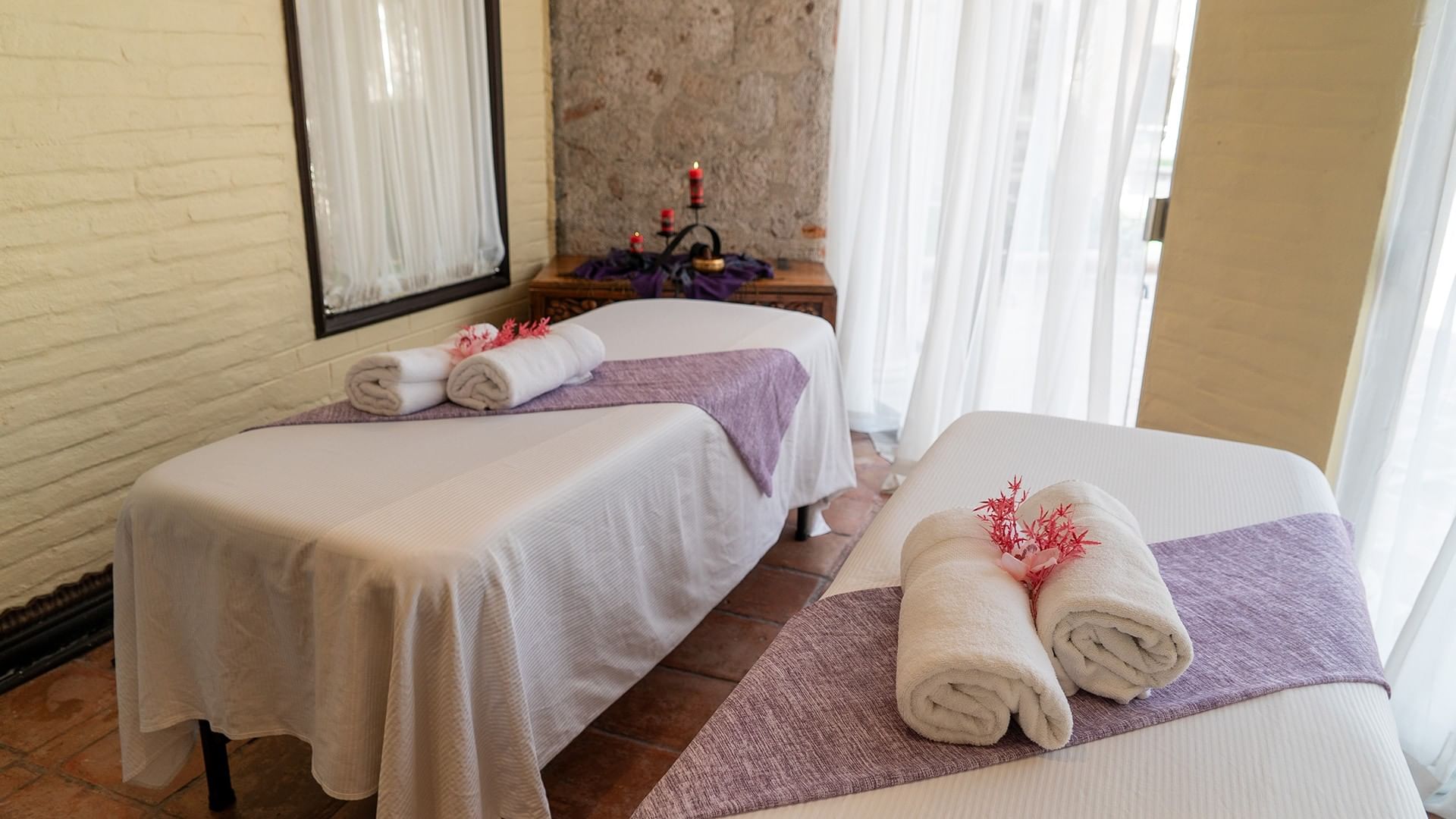 Two spa massage beds with purple runners and rolled towels at Quinta Real Aguascalientes