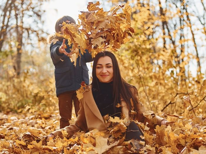 Woman and child playing in autumn leaves