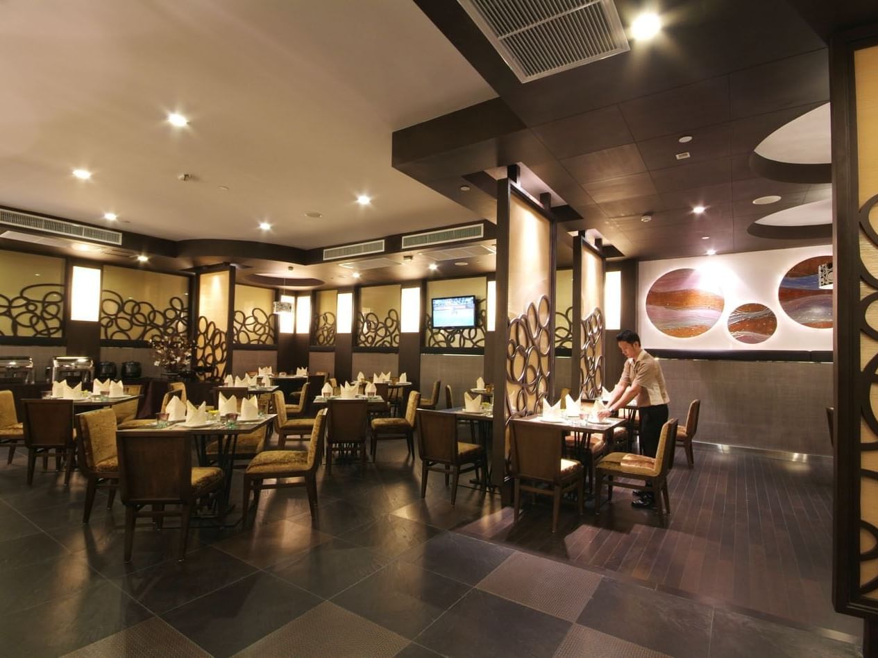 A waiter arrange dining tables in Neo Café at Amora Hotel