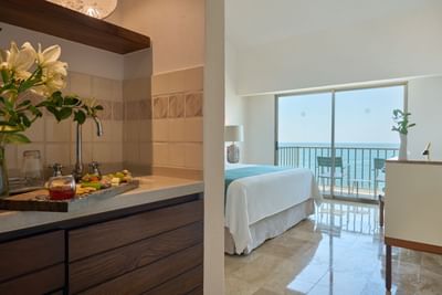 Interior view of a modern hotel suite entrance leading to a private balcony with panoramic ocean views.